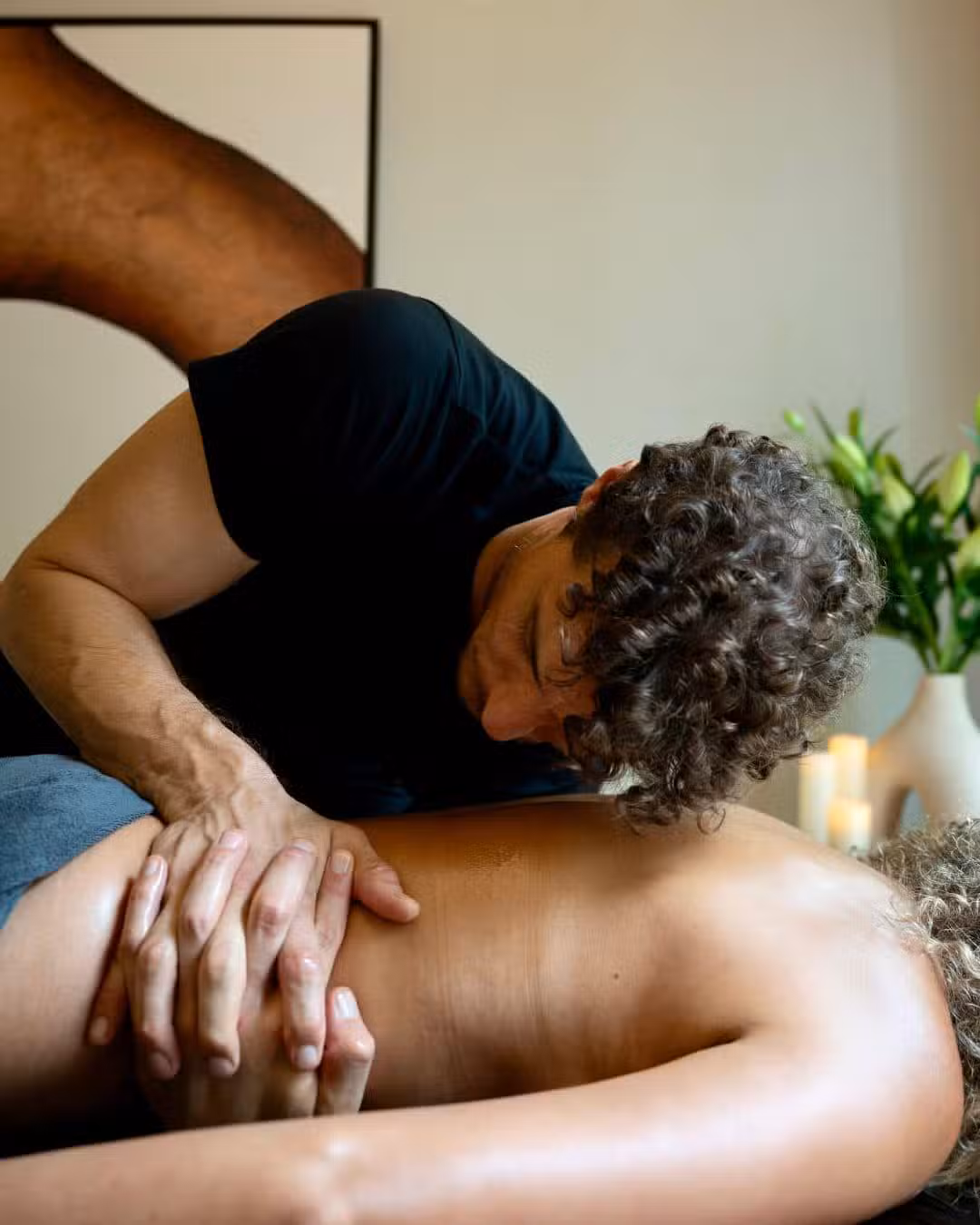 Praticienne en tenue professionnelle installant une table de massage avec linge blanc dans un salon parisien lumineux